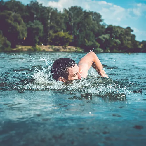 Person swimming in a lake surrounded by nature