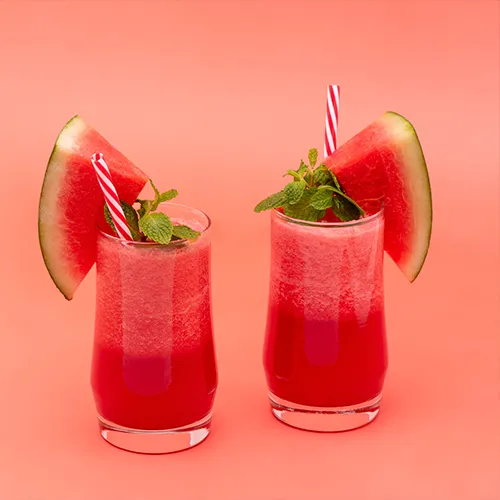 Image of a watermelon mint smoothie in a clear glass, garnished with mint leaves 