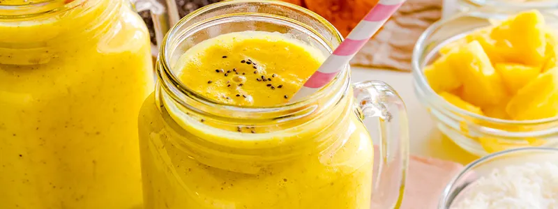 Image of a tropical pineapple coconut smoothie in a glass with pineapple chunks and shredded
