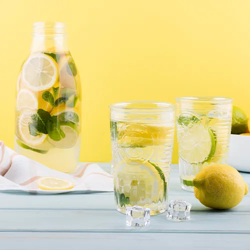 Glass of water with lemon and mint slices to stay hydrated in summer.