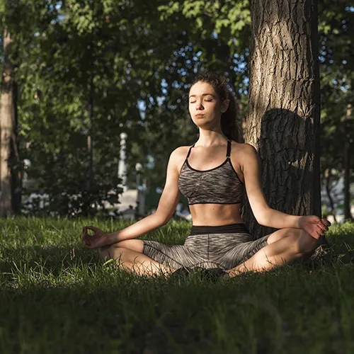 Person meditating in nature, surrounded by trees and peace.