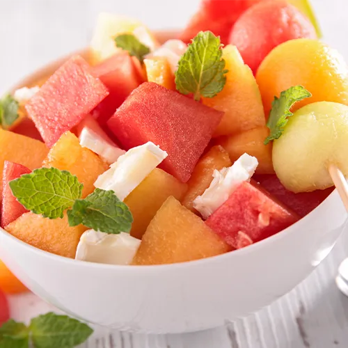 Frutas frescas como sandía y melón en una mesa para hidratarse en verano.