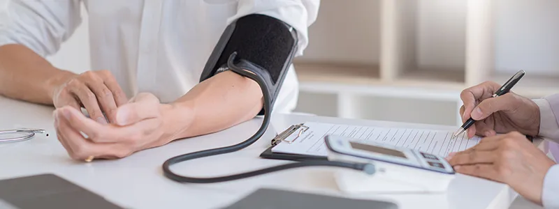 Doctor measuring a patient's blood pressure during a consultation.